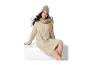 Femme en robe pull beige, bonnet et écharpe, assise.