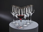 Un ensemble de six verres avec un bord doré, dont un rempli de vin rouge.