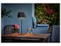 Lampe de table sur une table en bois avec des fleurs et une boisson sur une terrasse.
