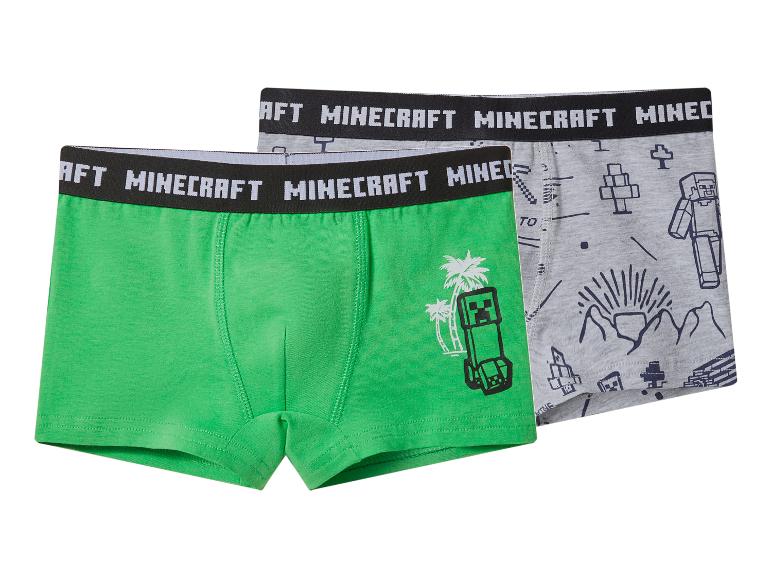 Deux boxers pour garçons, un vert avec un monstre et des palmiers, et un gris avec des motifs de personnages.