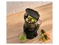 Extracteur de jus noir avec légumes coupés et un verre de jus vert sur une table en bois.