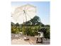 Un parasol blanc avec une chaise et une table dans un jardin.