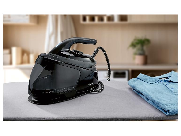 Système de repassage à vapeur noir avec réservoir d'eau sur une planche à repasser avec une chemise bleue.