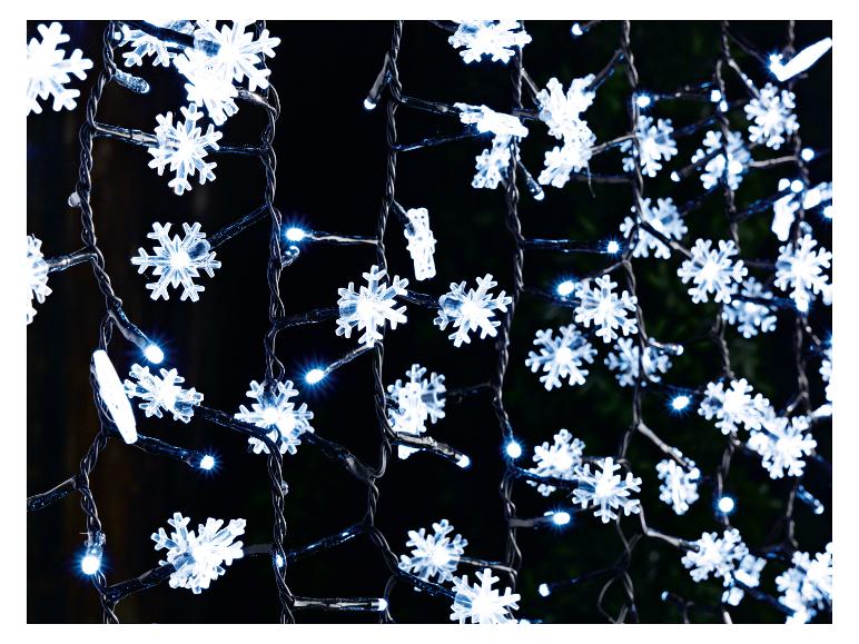 Gros plan de guirlandes lumineuses LED blanches en forme de flocon de neige sur fond sombre.