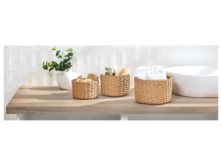 Trois paniers ronds en osier sur un comptoir en bois.