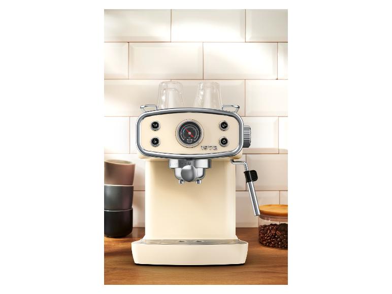 Machine à café rétro crème avec manomètre, sur un comptoir en bois avec tasses et grains de café.