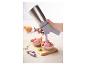 Une main utilise un siphon de cuisine pour verser de la mousse rose dans des bols de fruits secs.