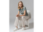 Une femme porte un chemisier bleu clair à imprimé, un pantalon blanc et des baskets blanches.