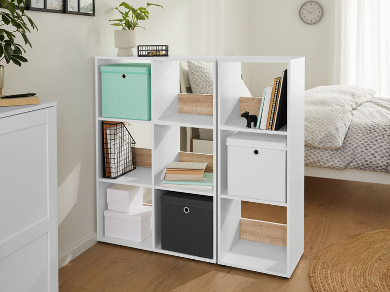 Étagère blanche avec des étagères, remplie de boîtes, de livres et de décorations.