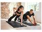 Deux personnes font des exercices avec une roue abdominale, des haltères et un tapis de fitness.