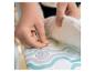 Mains fixant un tissu à motifs sur un rembourrage blanc.