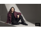 Femme assise par terre vêtue d'une doudoune bordeaux, d'un pantalon noir et de bottes.