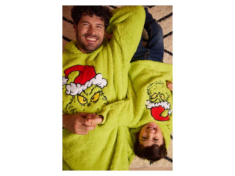 Père et fils souriants portant des sweats à capuche Grinch assortis