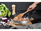 Wok avec nouilles, viande et légumes, mélangé avec une spatule en bois.