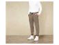 Un homme portant un haut blanc à manches longues et un pantalon de survêtement marron avec des baskets blanches.