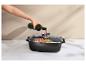 Main versant du vin rouge dans une cocotte avec couvercle en verre, contenant des aliments cuits.