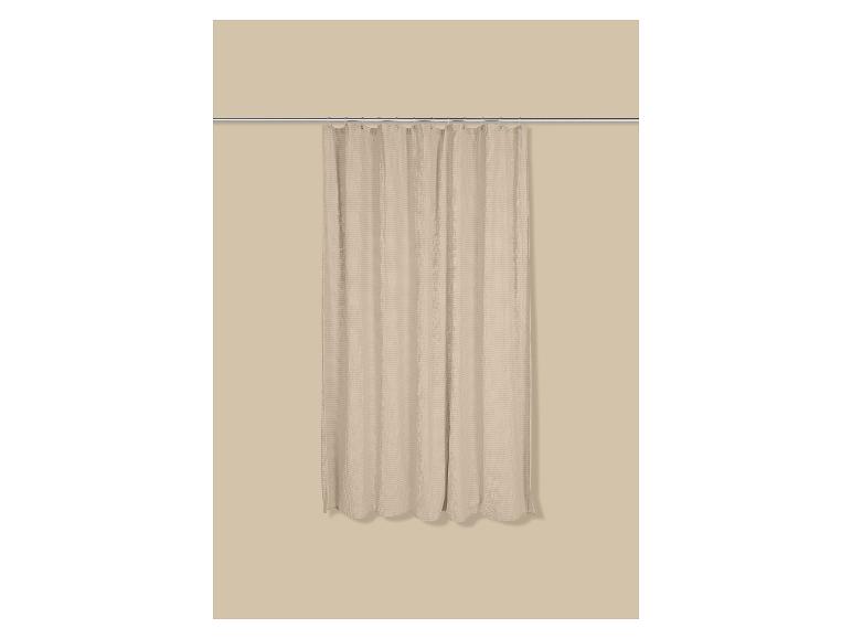 Rideau de douche beige avec motif texturé, suspendu à une tringle.