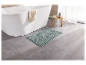 Un tapis de bain vert clair devant une baignoire blanche.