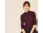 Femme portant un col roulé bordeaux et un pantalon en cuir noir.