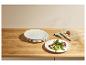 Assiettes blanches empilées et une assiette de viande et légumes sur une table en bois.