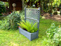 Un pot de fleurs gris avec une grille dans un jardin.