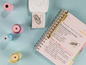 Un carnet avec un stylo doré, du papier pour étiquettes et une imprimante d'étiquettes.
