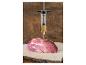 Injecteur de viande avec marinade, avec un morceau de viande crue sur une planche en bois.
