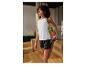 Femme en débardeur blanc et short noir s'étirant à l'intérieur.
