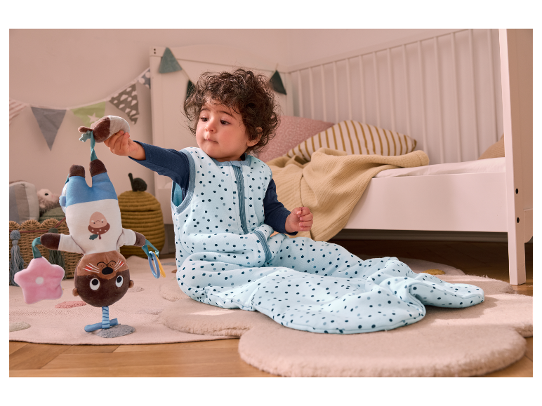 Bébé dans une gigoteuse avec un jouet.
