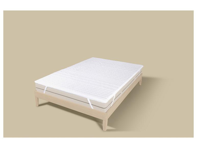 Matelas avec protège-matelas blanc sur un cadre de lit en bois