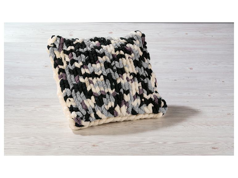 Coussin tricoté à la main en couleurs gris, noir et crème.