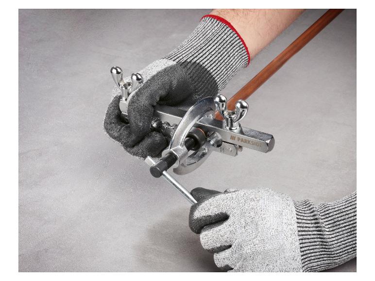 Mains gantées utilisant un kit d'évasement de tuyaux sur un tube en cuivre.