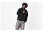 Homme en sweat à capuche noir avec motif et jean gris