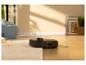 Robot aspirateur nettoyant un parquet et un tapis sous la lumière du soleil.