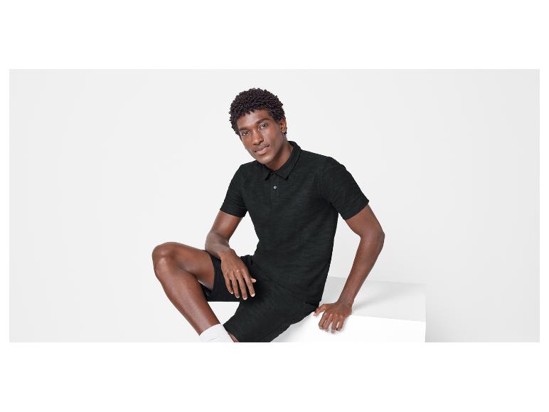Un homme portant un polo et un short noirs.
