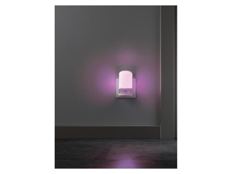 Veilleuse à brancher avec une douce lueur violette sur un mur gris.