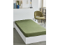 Drap-housse vert sur un lit blanc avec une table de chevet et une chaise.