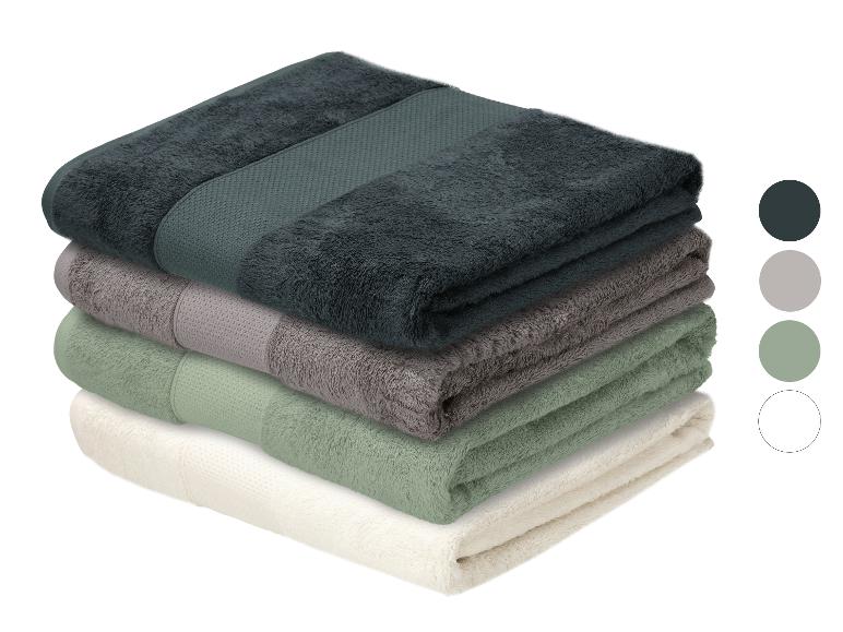 Pile de quatre serviettes pliées en gris foncé, gris, vert et blanc avec des échantillons de couleurs.