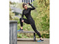 Une femme portant des vêtements de sport noirs et des chaussures de course bleues.