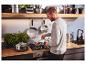Un homme cuisine avec une poêle et une casserole en acier inoxydable SILVERCREST® dans la cuisine.