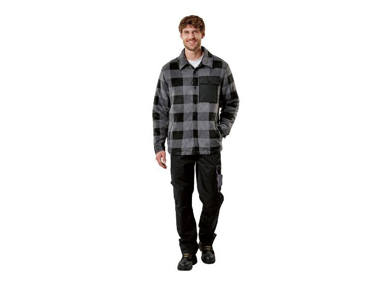 Homme en chemise à carreaux grise et noire, pantalon de travail noir et bottes.