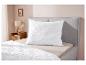 Couette et oreiller blancs matelassés sur un lit.