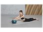 Une femme fait de l'exercice sur un tapis avec un ballon de fitness.
