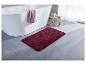 Tapis de bain bordeaux près d'une baignoire.