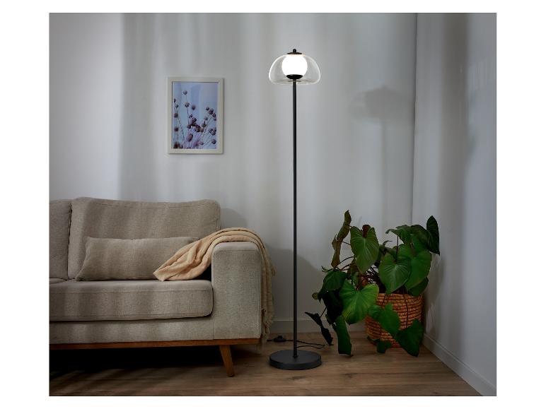 Lampe sur pied moderne avec abat-jour en verre, près d'un canapé.