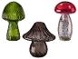 Trois champignons décoratifs en verre vert, marron et rouge avec des accents argentés.