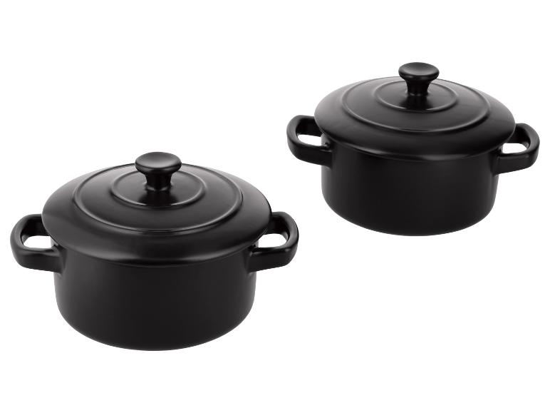 Deux cocottes individuelles noires en céramique avec couvercles.
