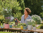 Une femme arrose des plantes avec un pulvérisateur Gardena.