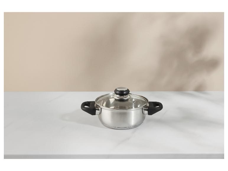 Casserole en acier inoxydable avec couvercle en verre sur une surface en marbre blanc.