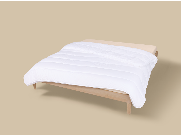 Couette blanche sur un cadre de lit en bois avec un matelas beige clair.